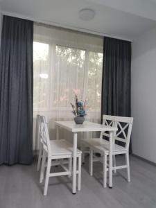 uma mesa branca e cadeiras num quarto com uma janela em Zenlux em Iaşi