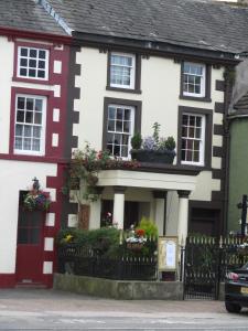 a white and red house with flowers in the window at Old Croft House in Kirkby Stephen