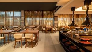 班加罗尔ibis Bengaluru Hebbal - An Accor Brand的有桌椅和窗户的餐厅