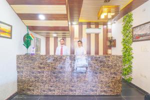 two men standing behind a marble counter in a room at The Glory Hotel in Dehradun