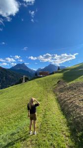 a woman standing on a grassy hill looking at a field at Hotel Almhof in San Candido