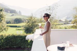 una mujer con un vestido blanco sosteniendo una copa de vino en Wellness Refugium & Resort Hotel Alpin Royal - Small Luxury Hotels of the World, en Cadipietra