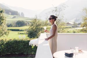 Eine Frau in einem weißen Kleid mit einem Glas Wein. in der Unterkunft Wellness Refugium & Resort Hotel Alpin Royal - Small Luxury Hotels of the World in Steinhaus