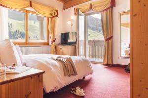 una camera d'albergo con letto e TV di Wellness Refugium & Resort Hotel Alpin Royal - Small Luxury Hotels of the World a Cadipietra