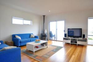 a living room with a blue couch and a tv at Chiaro Villa - Surf Side in Inverloch