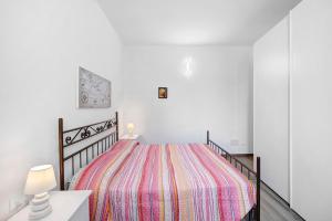 Dormitorio blanco con cama con manta a rayas en La Colombera en Alassio