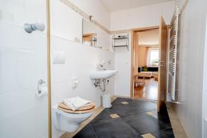 a white bathroom with a toilet and a sink at Hotel Donau-Ries in Mertingen