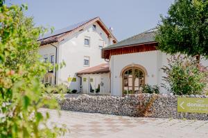 a large white house with a stone wall at Hotel Donau-Ries in Mertingen