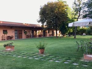 a house with a lawn with chairs and an umbrella at Agriturismo La Dondina in Budrio