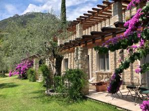 una casa de piedra con flores púrpuras en el patio en La Cascata Negli Ulivi, en Toscolano Maderno