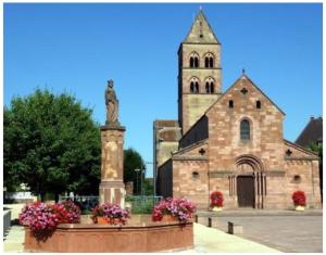a church with a statue in front of a building at Gîte avec SPA au cœur du vignoble d'Alsace in Sigolsheim