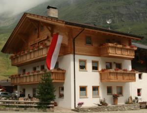 a building with wooden balconies and a flag on it at Thomashof in Pfelders