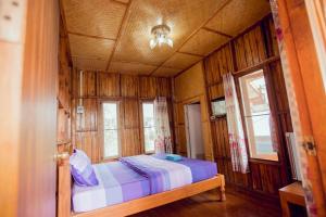 een slaapkamer met een bed in een kamer met ramen bij เขาค้อ กุหลาบแดง รีสอร์ท in Khao Kho