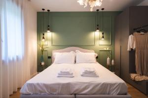 a bedroom with a white bed with a green headboard at AL TIGLIO in Farra di Soligo