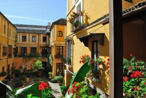 Blick aus einem Fenster auf einen Innenhof mit Blumen in der Unterkunft Hotel Las Casas de la Judería in Sevilla