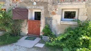 une maison ancienne avec une porte rouge et une fenêtre dans l'établissement Petit gîte à la ferme des buttons, à Rosnay