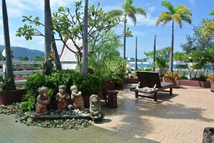 a garden with statues and a bench on a patio at Rayaburi Hotel, Patong in Patong Beach