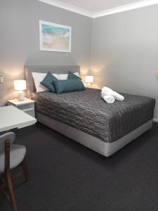 a bedroom with a bed with blue pillows at Solomon Inn Motel Figtree in Wollongong