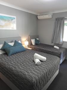 1 dormitorio con 2 camas y almohadas azules y blancas en Solomon Inn Motel Figtree, en Wollongong