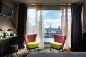 Zimmer mit 2 Stühlen und einem großen Fenster in der Unterkunft Helussi Hôtel in Paris