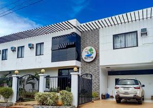 uma casa branca com um carro estacionado em frente dela em RedDoorz Plus at Palm Rise K Diving Resort Panglao Bohol em Panglao