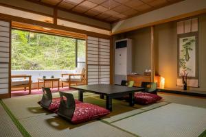 Nikko Nationalpark Kawamata Onsen KURA في نيكو: غرفة مع طاولة وكراسي ونافذة