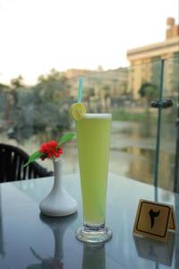 Nile Villa Hotel في القاهرة: وجود مشروب على طاولة مع مزهرية