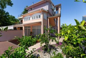 una grande casa rosa con piante di fronte di Malinsummer Apartments a Malinska