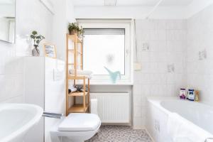 a bathroom with a tub and a toilet and a sink at Stay Awesome - Familien-Apartment am Botanischen Garten Kassel in Kassel