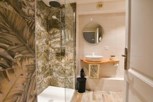 uma casa de banho com uma cabina de duche em vidro e um lavatório. em Au Fil du Temps em Sélestat