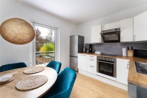 cocina con mesa de madera y sillas azules en Stay Awesome - Familien-Apartment am Botanischen Garten Kassel en Kassel