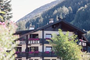 a building with flowers in front of a mountain at Hotel Auren in San Giovanni in Val Aurina