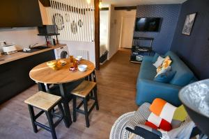 a kitchen and living room with a table and a blue couch at Au Fil du Temps in Sélestat +12 photos