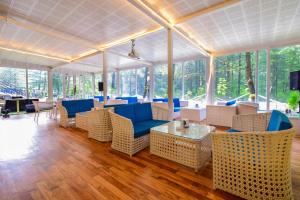 a lobby with blue chairs and tables and windows at Moksha Riverside Resort in Kasol