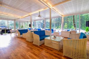 a lobby with blue chairs and tables and windows at Moksha Riverside Resort in Kasol