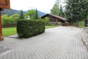 a brick driveway with a hedge in front of a house at Gästehaus Moser in Ranten