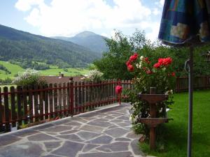 eine Terrasse mit einem Zaun, Blumen und einem Sonnenschirm in der Unterkunft Gästehaus Moser in Ranten