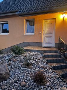 uma casa com uma porta amarela e um estaleiro de gravilha em Oase der Ruhe em Waldsieversdorf