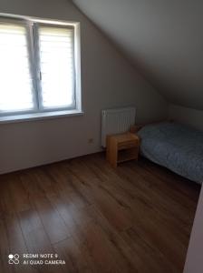 an attic bedroom with a bed and a wooden floor at DOMEK ANNY in Ropica Dolna