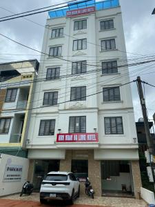 een wit gebouw met een auto ervoor geparkeerd bij Kim Ngan Ha Long Hotel in Ha Long