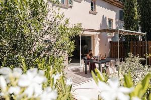 una mujer sentada en una mesa en un jardín en Les Maisons Du Sud, en Saint-Tropez