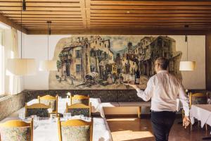 un hombre parado frente a un mural en un restaurante en Posthotel, en Lutago