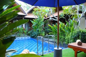 einen Pool mit Sonnenschirm neben einem Haus in der Unterkunft The Cemok's Cottage in Nusa Penida