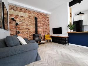 a living room with a couch and a brick wall at Bohema Apartement with private parking in Toruń