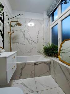 a bathroom with a tub and a marble wall at Bohema Apartement with private parking in Toruń +33 photos