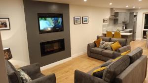 a living room with two couches and a television on a wall at Fabulous Belmullet Townhouse in Belmullet