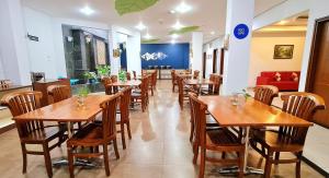 Hotel Dafam Rio في باندونغ: غرفة طعام مع طاولات وكراسي خشبية