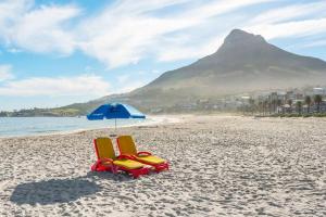 two chairs and an umbrella on a beach at Upmarket Urban Apartment in the East City w/ Vi in Cape Town