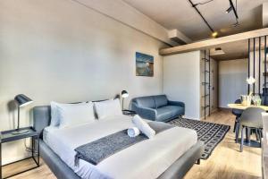 ein Schlafzimmer mit einem großen Bett und einem blauen Stuhl in der Unterkunft Upmarket Urban Apartment in the East City w/ Vi in Kapstadt