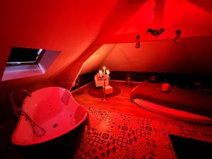 ein rotes Zimmer mit einer Badewanne und einem Bett mit Kerzen in der Unterkunft Redroom Loveroom Chambre Spa privative Insolite Thème 50 nuances de grey in Douchy-les-Mines